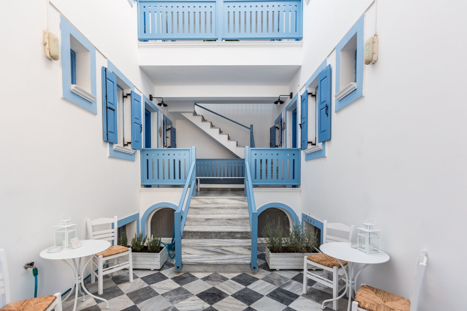 Courtyard of Fanouris Condo with chequered marble floor, bistro tables and blue railings